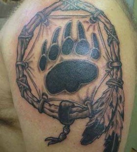 Black pawprints of bear tattoo on shoulder