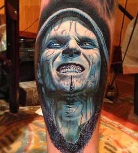 Blue men's face tattoo on leg