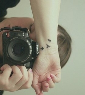 Canon camera and black bird tattoo on arm