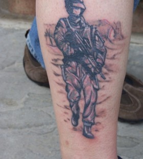 Soldier with gun leg tattoo