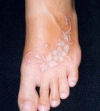 white ink tattoo flowers on a foot