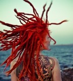 tattooed girl with dreadlocks back tattoo red dreads beach