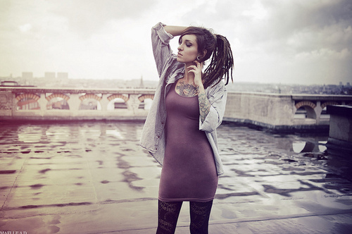 tattooed girl with dreadlocks grey sky chest and arm tattoos