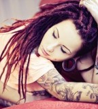 tattooed girl with dreadlocks red hair on couch