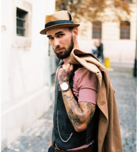 man with tattoos holding a jacket