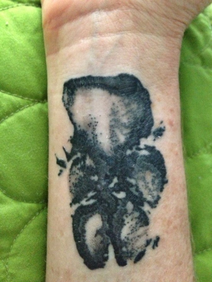 Awesome black pawprints dog tattoo on arm