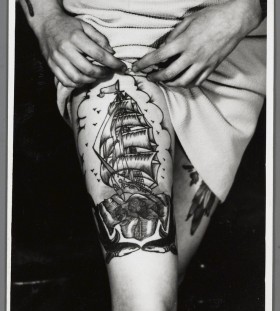 Black and white ship tattoo on leg