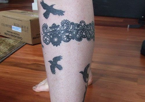 Black bird and lace tattoo on leg