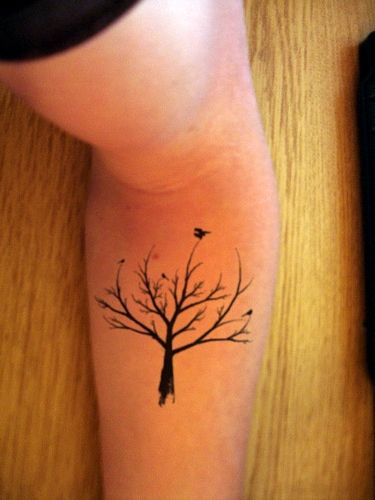 Black bird and tree tattoo on arm