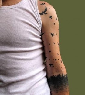 Black forest and bird tattoo on arm