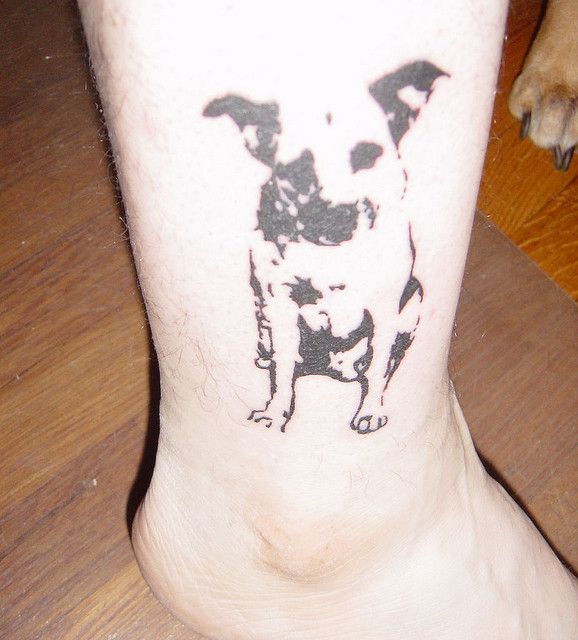 Black small dog tattoo on leg