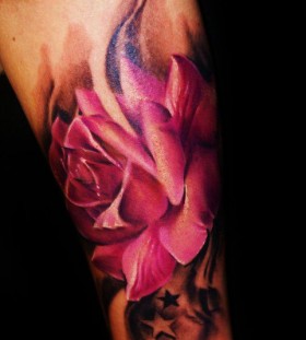 Black stars and pink rose tattoo on arm