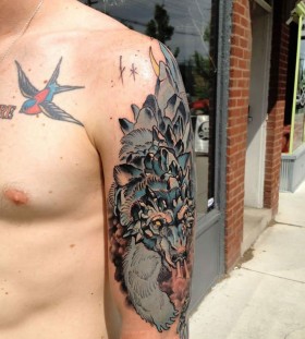 Blue bird and wolf tattoo on arm