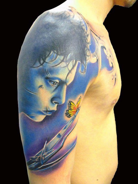 Blue face and butterfly tattoo on arm