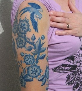 Blue flowers and birds tattoo on arm