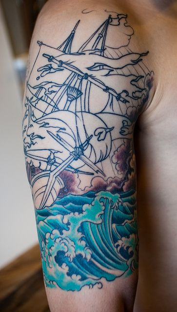 Blue water and black ornaments of ship tattoo on arm
