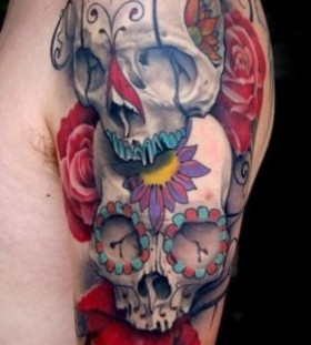 Colorful flowers and skull tattoo on shoulder