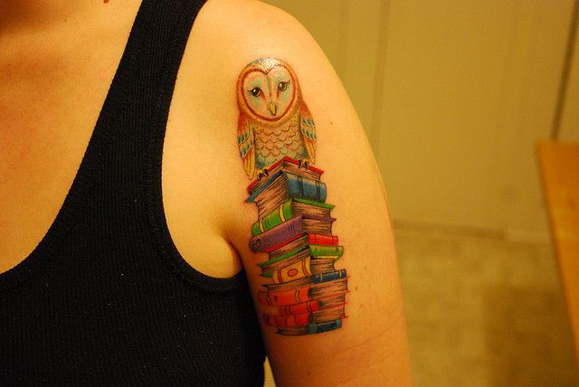 Colorful owl and book tattoo on arm
