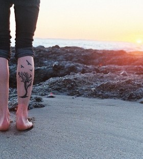 Cute sunset and tree tattoo on leg