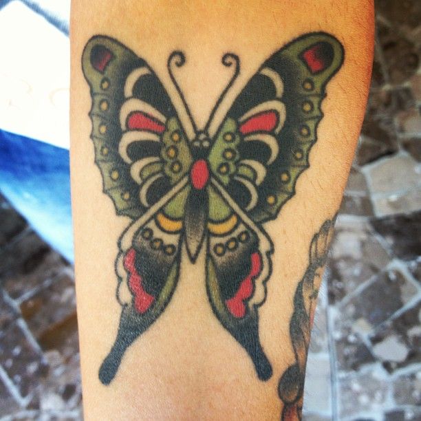 Green and red butterfly tattoo on leg