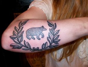 Leafs and black bear tattoo on arm