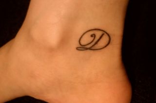 Letter D and quote tattoo on leg