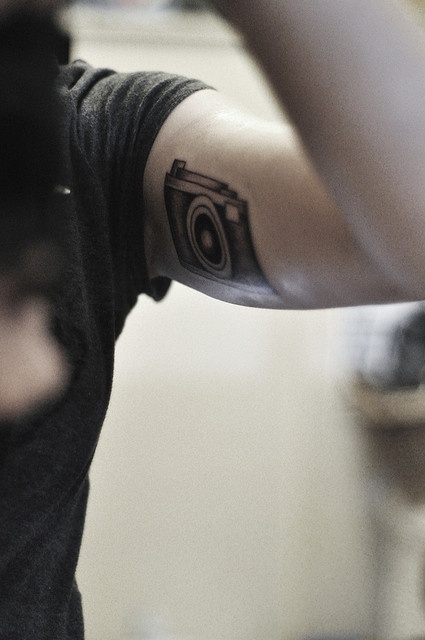Lovely black camera tattoo on arm