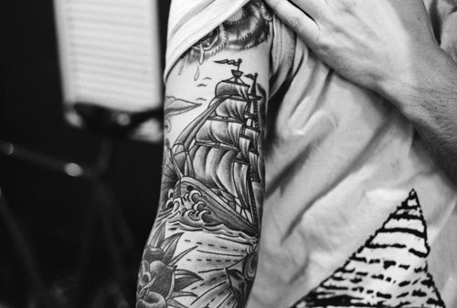 Men’s black ship tattoo on arm