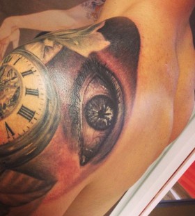 Old watch and eye tattoo on shoulder