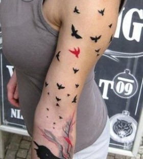 Red and black bird tattoo on arm