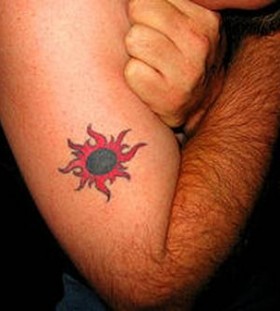 Red and black sun tattoo on arm