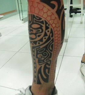 Red and black sun tattoo on leg