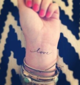 Red nails and love tattoo on arm