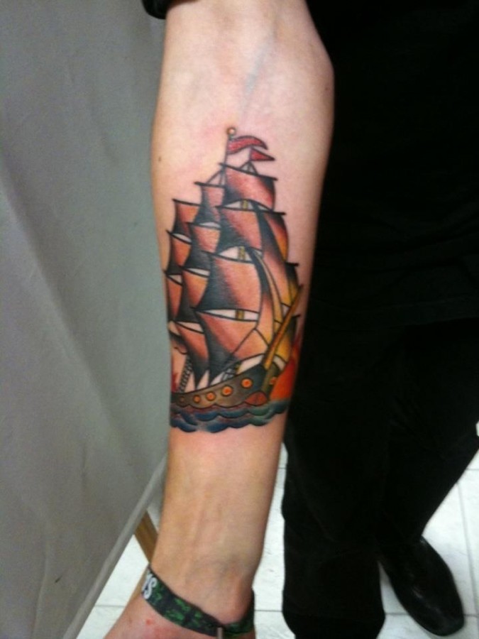 Red simple ship tattoo on arm