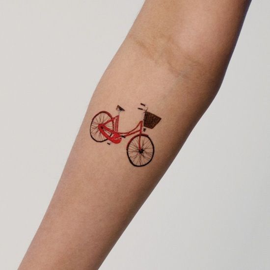 Red small lovely bicycle tattoo on arm