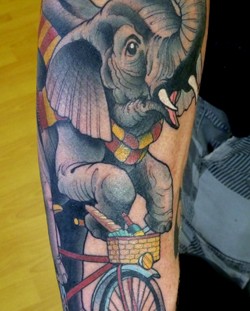 Riding elephant with bicycle tattoo on arm