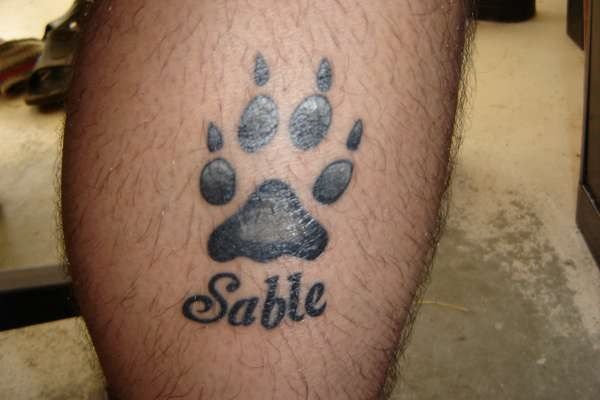 Sable pawprint dog tattoo on leg