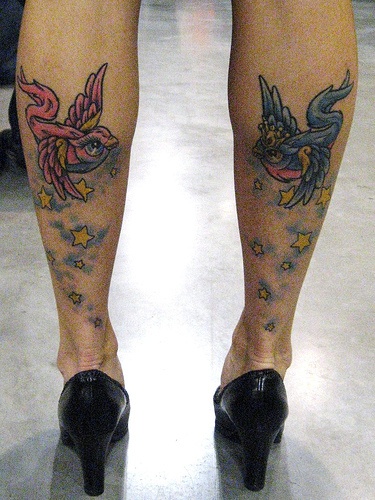 Stars and colorful birds tattoos on legs
