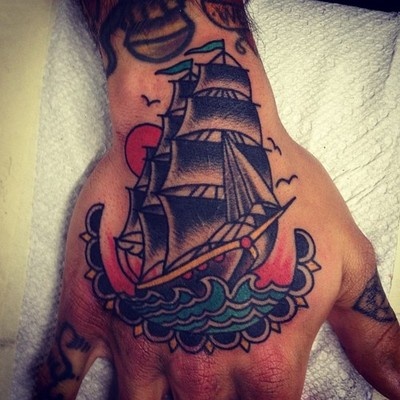 Sun, birds and ship tattoo on arm