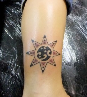 Traditional black sun tattoo on leg