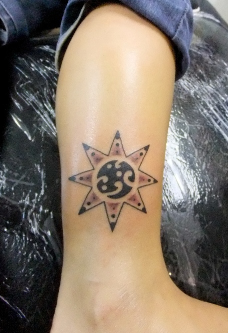 Traditional black sun tattoo on leg