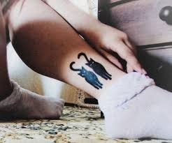 Two black cats tattoo on leg