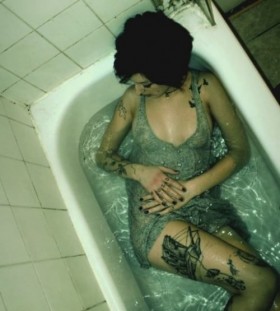 Women in bath and bird tattoo on leg