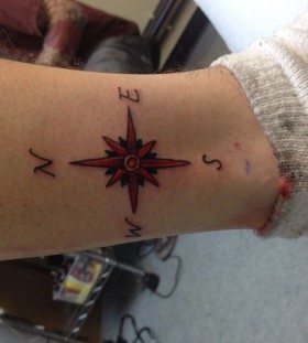 Red small compass tattoo on leg