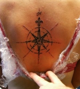 Simple women's compass tattoo on back