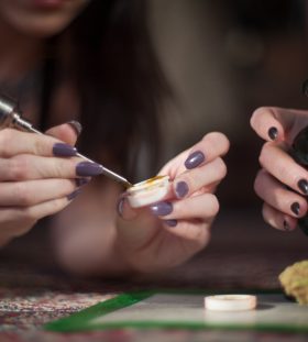 Women with nicely manicured fingernails use a titanium dabber to