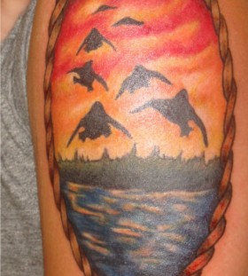Birds and sunset arm tattoo