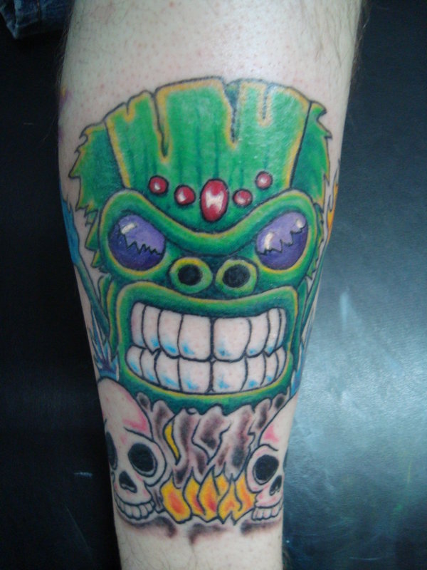 Green tiki and skulls tattoo
