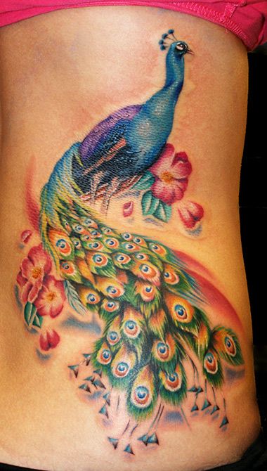 Peacock on woman’s body watercolor tattoo