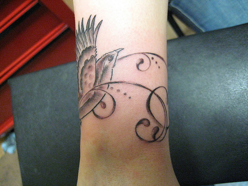Black And Grey Swirly Bird Wrist Tattoo